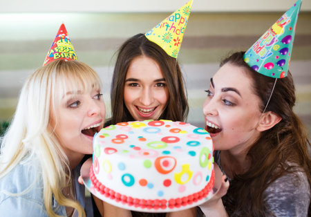 Birthday. Girls bite cake at a birthday partyの写真素材