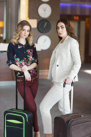 Meeting at the hotel reception, girls with suitcases in the hotel lobbyの写真素材