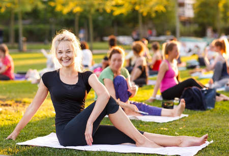 big group of adults attending a yoga class outside in parkの写真素材