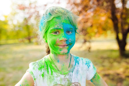 Portrait of a cute girl painted in the colors of Holi festival.の写真素材