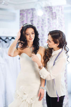 Female trying on wedding dress in a shop with women assistant.の写真素材
