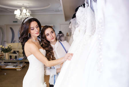Female trying on wedding dress in a shop with women assistant.の写真素材