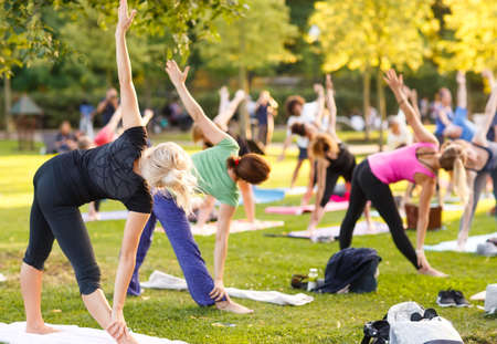 big group of adults attending a yoga class outside in parkの写真素材