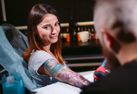 Professional tattoo artist makes a tattoo on a young girls hand.