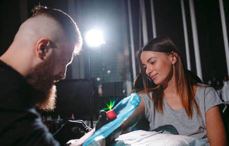 Professional tattoo artist makes a tattoo on a young girls hand.の写真素材