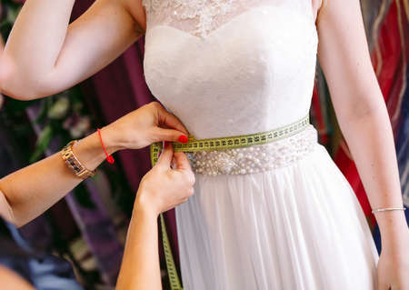 Female trying on wedding dress in a shop with women assistant.の写真素材