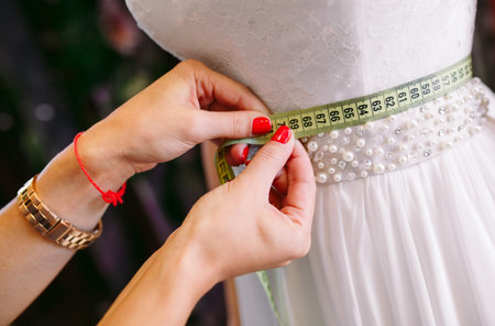 Female trying on wedding dress in a shop with women assistant.