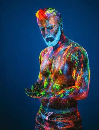 Concept. Portrait of a bearded man. The man is painted in ultraviolet powder.