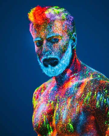 Concept. Portrait of a bearded man. The man is painted in ultraviolet powder.の写真素材