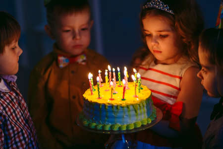 Childrens birthday. Children near a birthday cake with candlesの写真素材