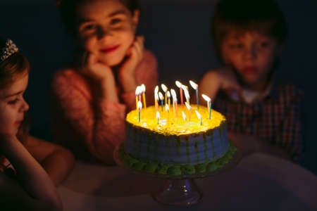 Childrens birthday. Children near a birthday cake with candlesの写真素材