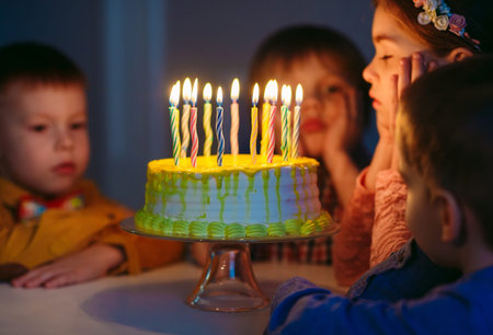 Childrens birthday. Children near a birthday cake with candles.