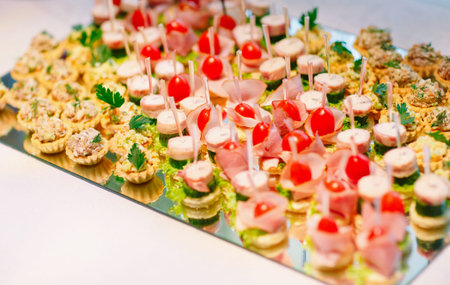 Assortment of canapes with fresh vegetables and salad. Banquet service.