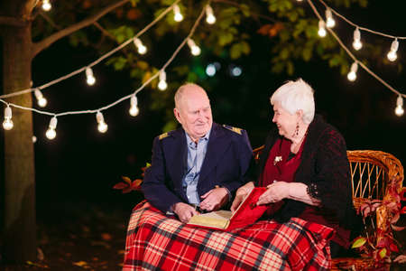 Happy memories. Happy senior couple sitting on sofa watching album with photosの写真素材