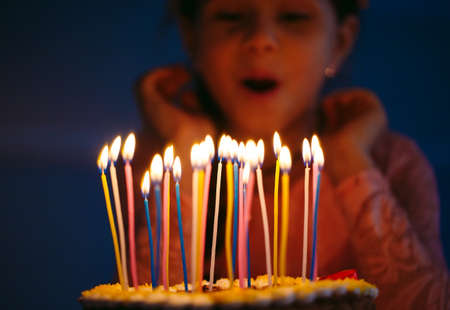Birthday. A little sweet girl blows out candles on the stokeの写真素材