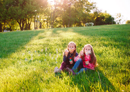 Girls play with soap bubbles in a spring time.