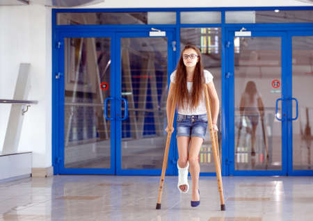 A young girl is on crutches in the corridor of the hospitalの写真素材