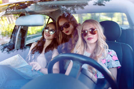 Three young girlfriends traveling in a car.の写真素材