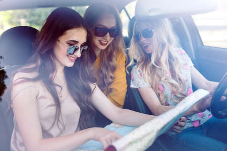 Three young girlfriends traveling in a car.の写真素材