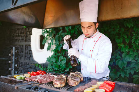 The Chef prepares meat on the barbecue.の写真素材