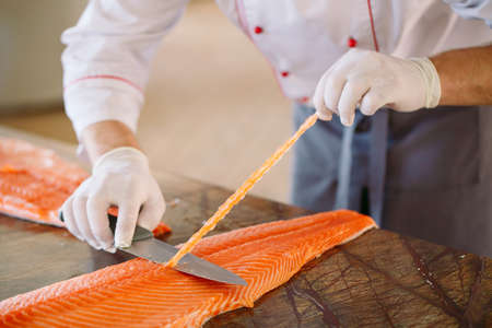 The chef cuts the salmon on the table.の写真素材