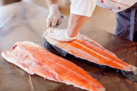 The chef cuts the salmon on the table