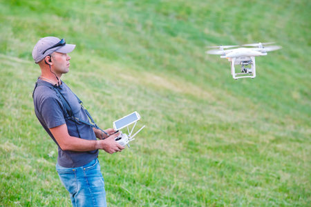 Young Man watching and navigating a flying drone