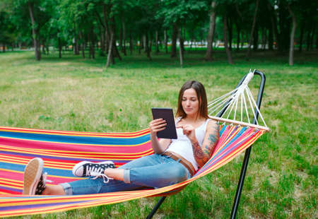 Young woman with tablet on the hammock.の写真素材