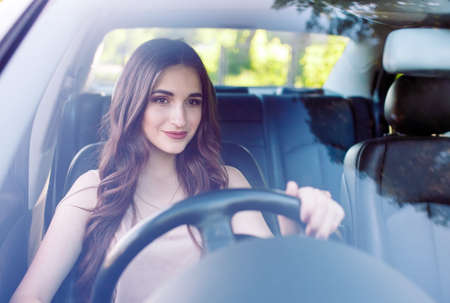 A young beutiful girl is driving a car.の写真素材