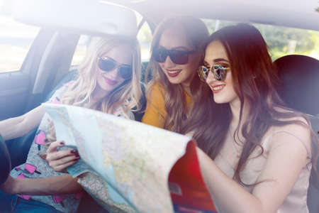 Three young girlfriends traveling in a car.の写真素材