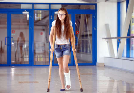 A young girl is on crutches in the corridor of the hospital.の写真素材