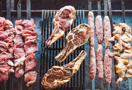 Large pieces of pickled meat on a grid in a restaurant. Mixed grilled meats.の写真素材