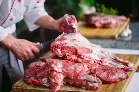 A man cook cuts meat with a knife in a restaurantの写真素材