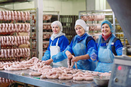 Butchers processing sausages at a meat factory.の写真素材