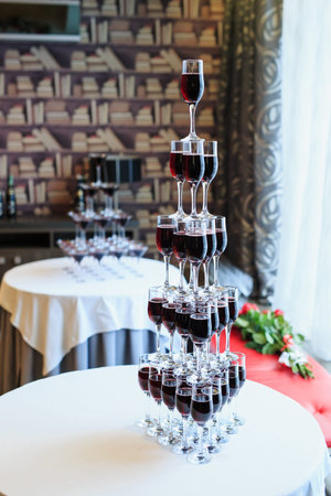 Waiter pouring red wine or champagne into glasses for party.