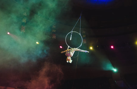 Aerial acrobat in the ring. A young girl performs the acrobatic elements in the air ring.