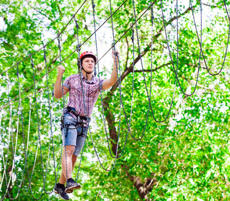 adventure climbing high wire park - people on course in mountain helmet and safety equipmentの写真素材