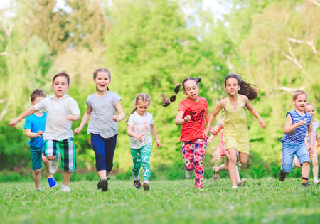 Many different kids, boys and girls running in the park on sunny summer day in casual clothes.の写真素材