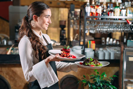 Waiter serving in motion on duty in restaurant. The waiter carries dishes.の写真素材