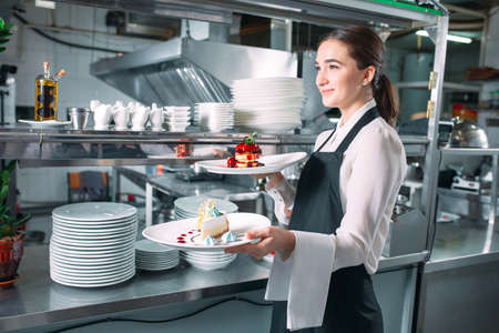Waiter serving in motion on duty in restaurant. The waiter carries dishes.の写真素材
