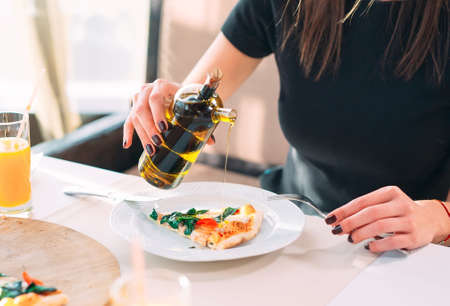 The girl pours oil a tasty Pizza.の写真素材