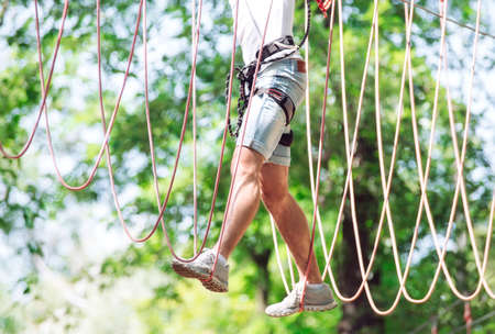 Man spend their leisure time in a ropes course. Man engaged in rope park.の写真素材