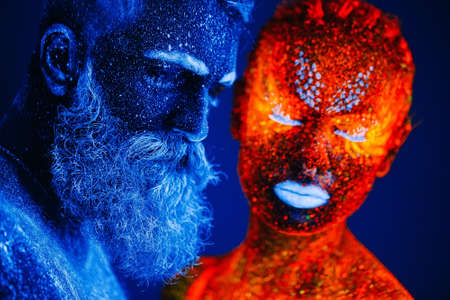 Concept. Portrait of a bearded man and woman painted in ultraviolet powderの写真素材