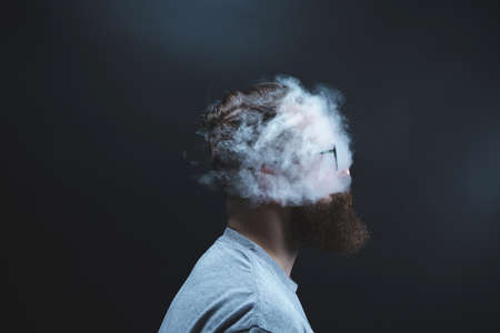Concept. Smoke enveloped the head man. Portrait of a Bearded, stylish man with smoke. Secondhand smoke.の写真素材