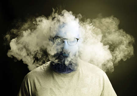 Concept. Smoke enveloped the head man. Portrait of a Bearded, stylish man with smoke. Secondhand smoke.の写真素材