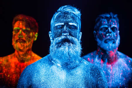 Portrait of three bearded men painted in florescent powdersの写真素材