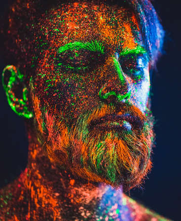 Concept. Portrait of a bearded man. The man is painted in ultraviolet powderの写真素材