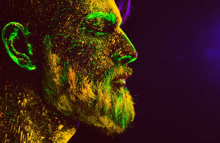Concept. Portrait of a bearded man. The man is painted in ultraviolet powderの写真素材