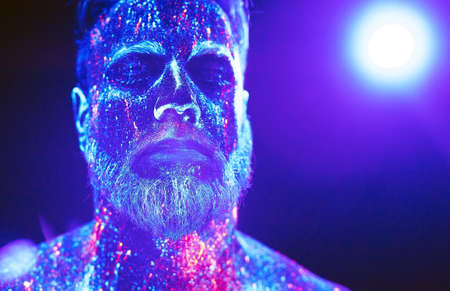 Concept. Portrait of a bearded man. The man is painted in ultraviolet powderの写真素材