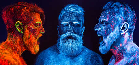 Portrait of three bearded men painted in florescent powdersの写真素材